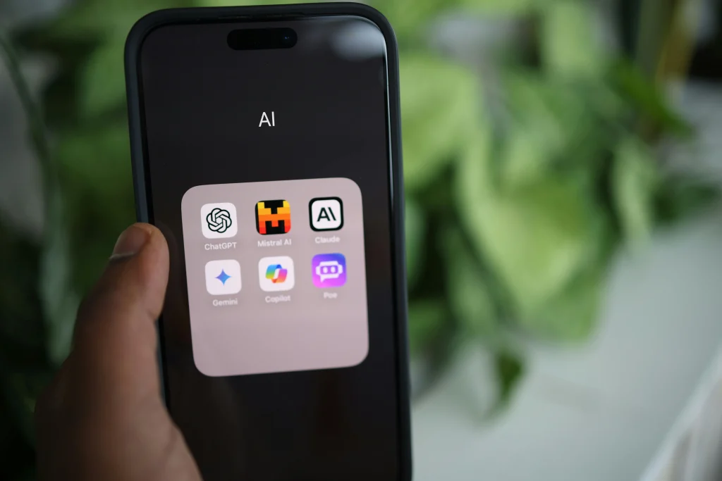 A person holding a phone with AI apps like ChatGPT Gemini Mistral AI Copilot Claude on it